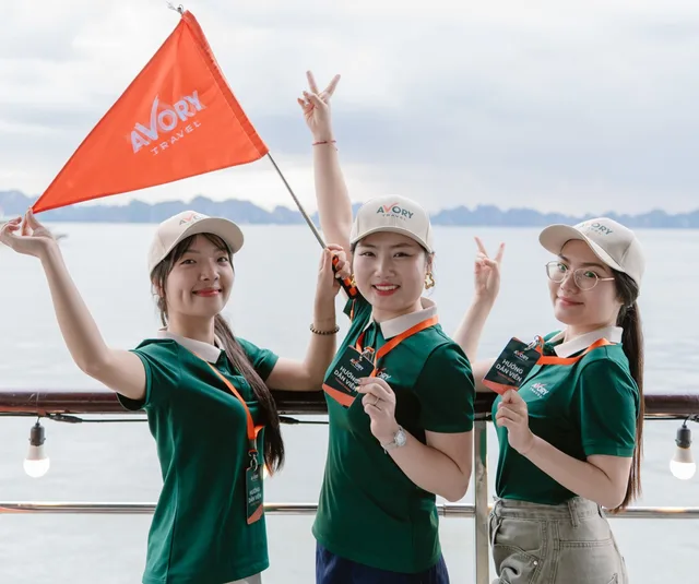 Ba hướng dẫn viên Avory Travel cầm cờ thương hiệu trên du thuyền vịnh Hạ Long